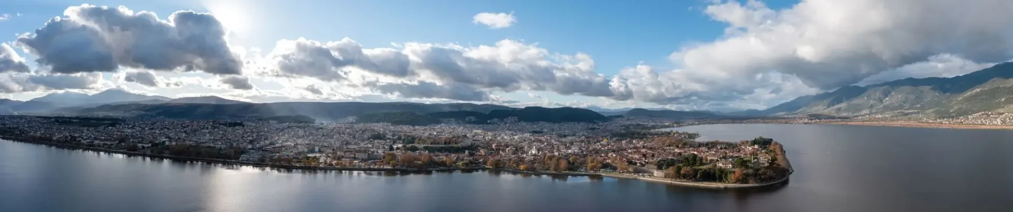 Greece, Ioannina  city. Aerial panoramic drone view of Giannena and Lake Pamvotis, cloudy blue sky. Epirus.